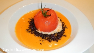 Tomate, mit Meeresfrüchten gefüllt, auf schwarzem Reis